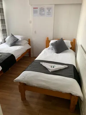 two beds in a room with white walls at Alderley Hotel Blackpool in Blackpool