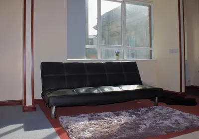 a black leather couch in a room with a window at Renshaw Guest House in Liverpool