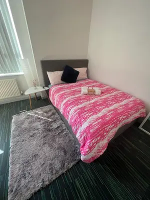 a bedroom with a bed with a pink blanket and a rug at Renshaw Guest House in Liverpool
