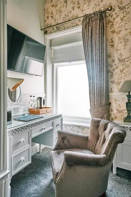 a living room with a chair and a desk and a window at The Queens Hotel in Lytham St Annes
