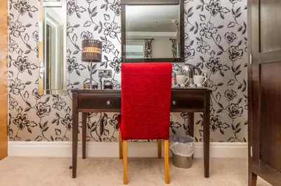 a bathroom with a red chair in front of a mirror at Number One South Beach in Blackpool