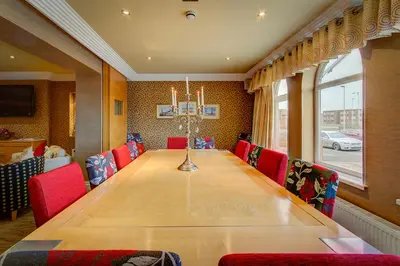a dining room with a long table and red chairs at Number One South Beach in Blackpool