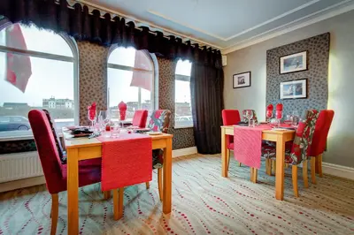 a dining room with two tables and red chairs at Number One South Beach in Blackpool