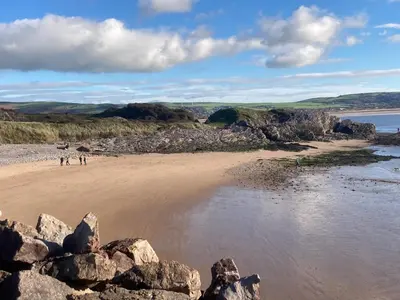 a beach with some people standing on the sand at HH Accommodation in Millom