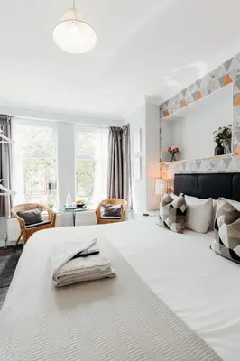 a bedroom with a large white bed and a living room at Sweet Suites Lytham in Lytham St Annes