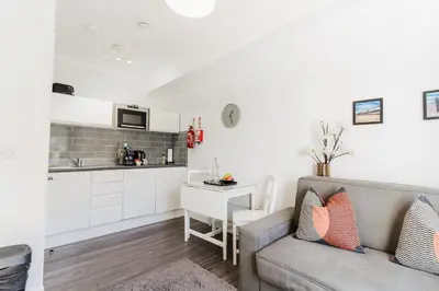 a living room with a couch and a kitchen at Sweet Suites Lytham in Lytham St Annes