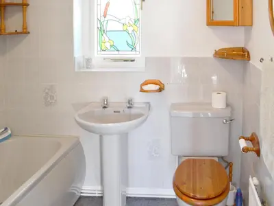 a bathroom with a sink and a toilet and a window at Carmichael in Longridge
