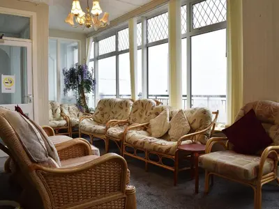 a waiting room with couches and chairs and windows at Ocean View House in Blackpool