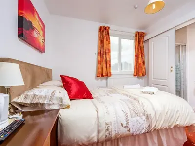 a bedroom with a bed with red pillows and a desk at Holmeleigh Hotel in Blackpool