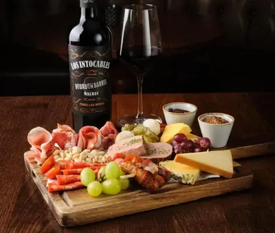 a wooden table with a plate of food and a bottle of wine at Arthur's Bar & Accommodation in Southport