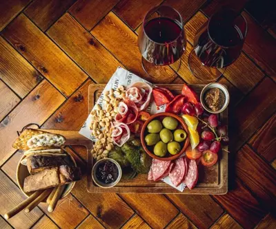 a wooden table with a tray of food and wine glasses at Arthur's Bar & Accommodation in Southport