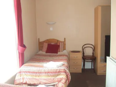 a small bedroom with a bed and a chair at Boltonia in Blackpool