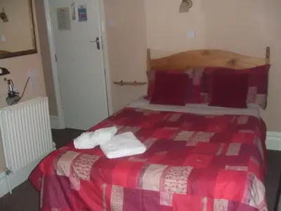 a bedroom with a red and white bed with towels on it at Boltonia in Blackpool