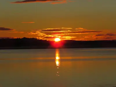 a sunset over a body of water with the sun setting at The Bay Horse Hotel And Restaurant in Ulverston