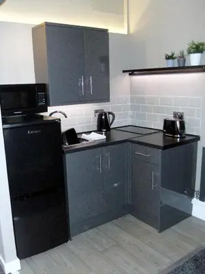 a kitchen with black cabinets and black appliances at Dewsbury House in Blackpool
