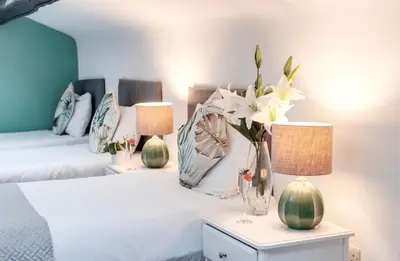 a bedroom with two beds and two lamps and flowers at Elysium Liverpool in Liverpool