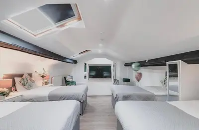 a bedroom with three beds and a couch at Elysium Liverpool in Liverpool