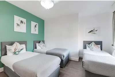 three beds in a room with green and white walls at Elysium Liverpool in Liverpool