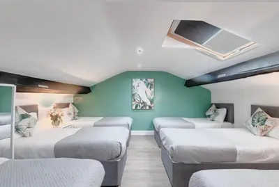a room with four beds and a blue wall at Elysium Liverpool in Liverpool