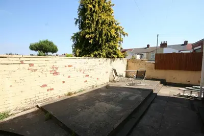 a brick wall with a table and chairs in a yard at MARLEY MANSIONS APARTMENT - Clarendon in Wallasey