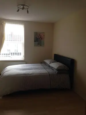 a bedroom with a large bed with a window at MARLEY MANSIONS APARTMENT - Clarendon in Wallasey