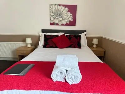 a bedroom with a red bed with towels on it at The Aberford in Blackpool