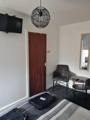 a bedroom with a bed and a chair and a table at The Last Post in Blackpool