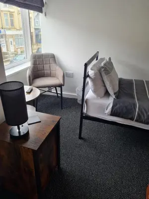 a bedroom with a bed and a chair and a table at The Last Post in Blackpool