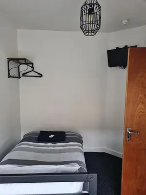 a bed in a room with a white wall at The Last Post in Blackpool