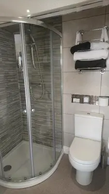 a bathroom with a shower and a toilet and towels at The Gatsby Blackpool - Formerly The Windsor in Blackpool