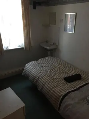 a small bedroom with a bed and a sink at The Midway in Blackpool