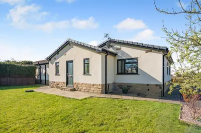 a detached house with a lawn in front of it at Palms Cottage in Blackburn