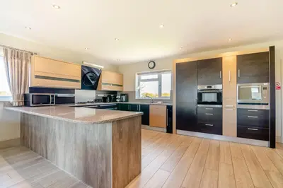 a large kitchen with black appliances and wooden cabinets at Palms Cottage in Blackburn