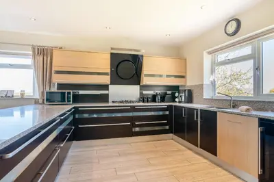 a kitchen with wooden cabinets and a large window at Palms Cottage in Blackburn