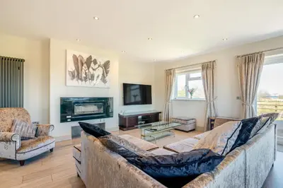 a living room with a couch and a tv at Palms Cottage in Blackburn