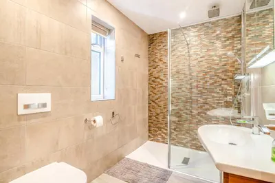 a bathroom with a glass shower and a sink at Palms Cottage in Blackburn