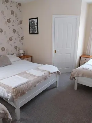 a bedroom with two beds and a door at Delamere Hotel in Blackpool