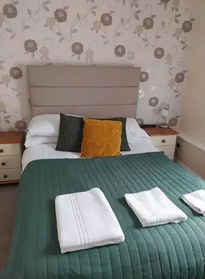 a bedroom with a green bed with towels on it at Delamere Hotel in Blackpool
