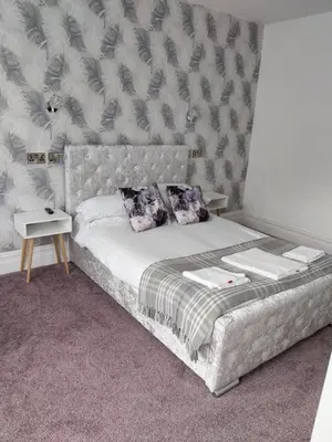 a bedroom with a bed with a headboard and pillows at Delamere Hotel in Blackpool