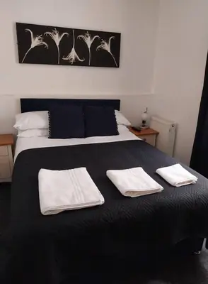 a black bed with two white towels on it at Delamere Hotel in Blackpool