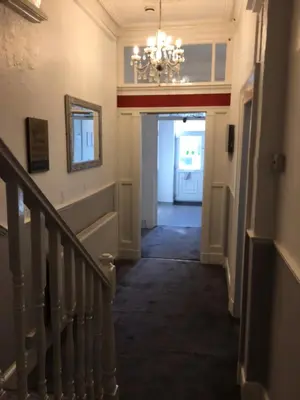 a hallway of a home with a staircase and a chandelier at MyRoomz Seaview Hotel in Blackpool