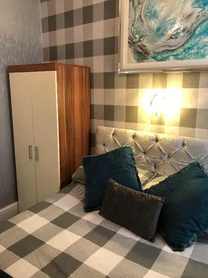 a bedroom with a bed with pillows and a painting at Baxter Holiday Apartments in Blackpool