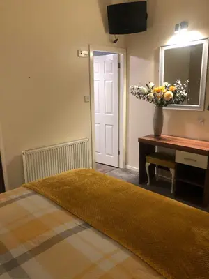a bedroom with a bed with a vase of flowers on a table at Baxter Holiday Apartments in Blackpool