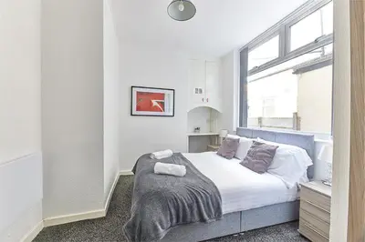 a bedroom with a bed with white sheets and a window at Pleasure Holiday Apartments in Blackpool
