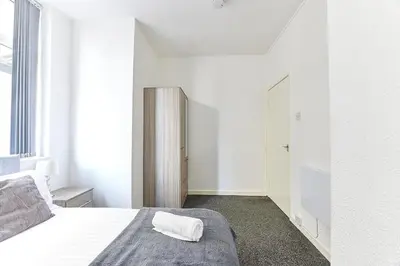 a white bedroom with a bed with a towel on it at Pleasure Holiday Apartments in Blackpool
