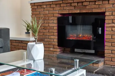 a living room with a brick fireplace and a table at Pleasure Holiday Apartments in Blackpool