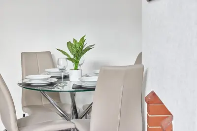 a dining room table with white chairs and a plant at Pleasure Holiday Apartments in Blackpool
