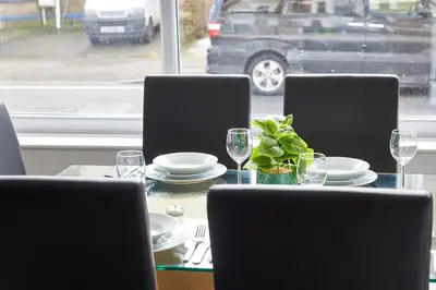 a table with chairs and plates and wine glasses at Pleasure Holiday Apartments in Blackpool