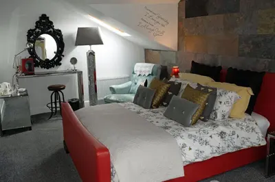 a bedroom with a bed and a chair and a mirror at The Arthington in Blackpool