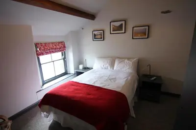 a bedroom with a bed with a red blanket and a window at The Warehouse in Ulverston